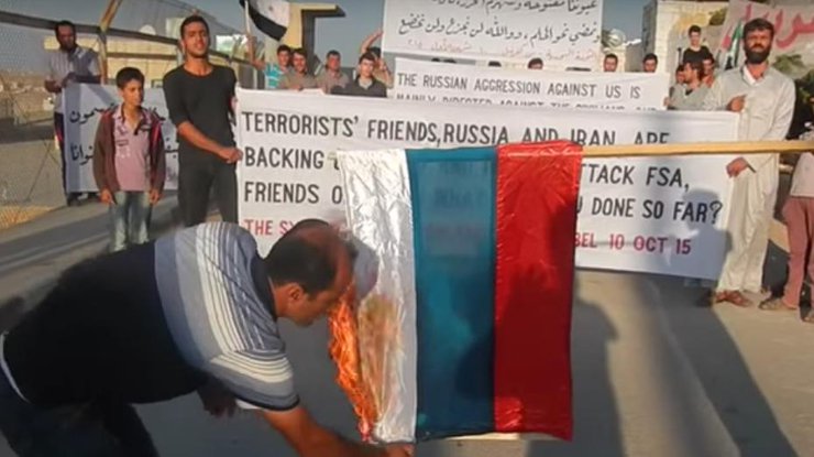 Сирийцу жгут флаг России. Кадр из видео