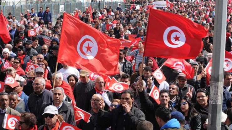 Люди держали в руках флаги Туниса