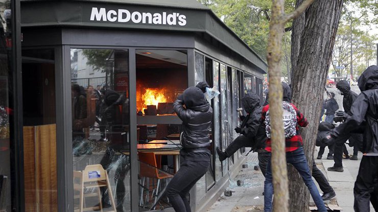 Протестующие начали громить витрины ресторанов и кафе.