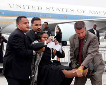 Сотрудники спецслужб оттаскивают журналистку от самолета Обамы. Фото AP
