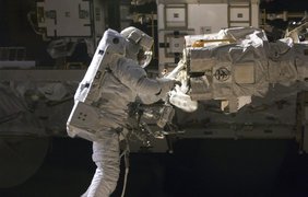 Астронавт Роберт Сэтчер работает в открытом космосе возле МКС, 19 ноября 2009 года