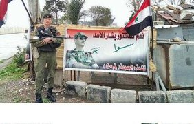 Военный из России на фоне сирийских флагов