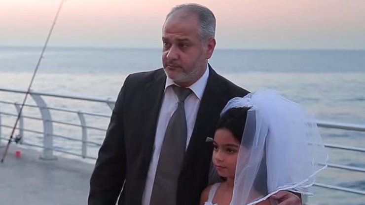 Девочка которой всего 12 лет в белом платье и фате позирует со своим мужем, который годится ей в дедушки.