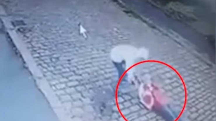 На видео мужчина хватает сумку, но пострадавшая не отпускает ее, после чего падает