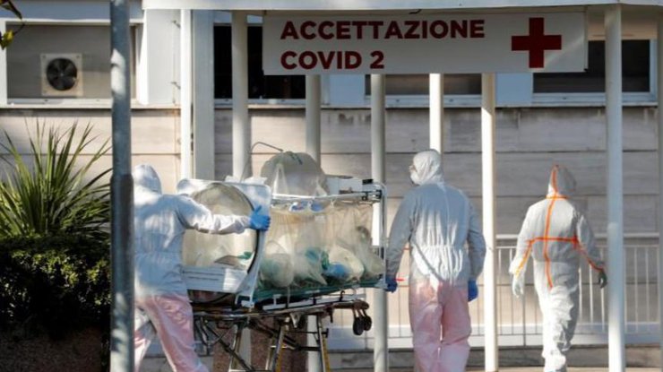 Медицинские работники в защитных костюмах доставляют пациентов в больницу Рима/REUTERS