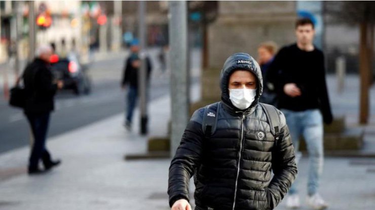 Мужчина в защитной маске на улице Лондона/Reuters