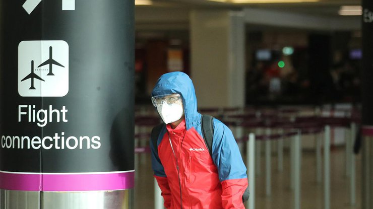 Мужчина в защитной маске ожидает эвакуации в аэропорту/Reuters
