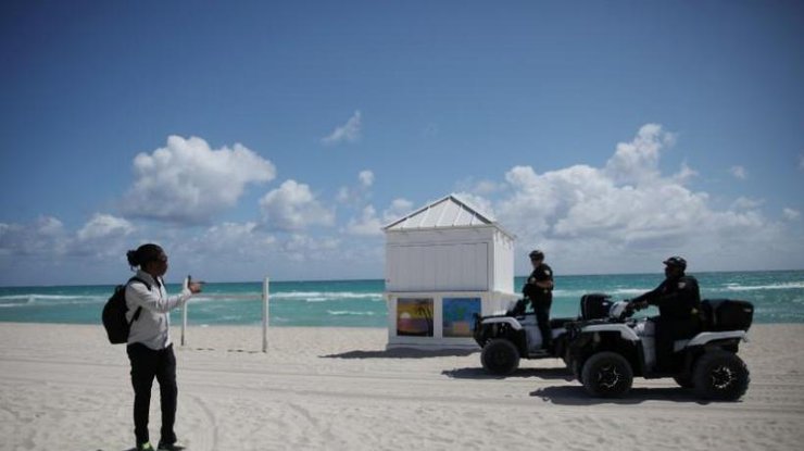 Полицейские на пляже в Калифорнии просят мужчину вернуться домой, 19 марта 2020 года/REUTERS