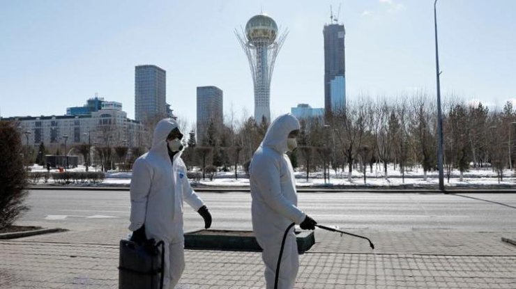 Рабочие в защитных костюмах распыляют дезинфицирующее средство на улицах Нур-Султана, Казахстан, 24 марта 2020 года/REUTERS
