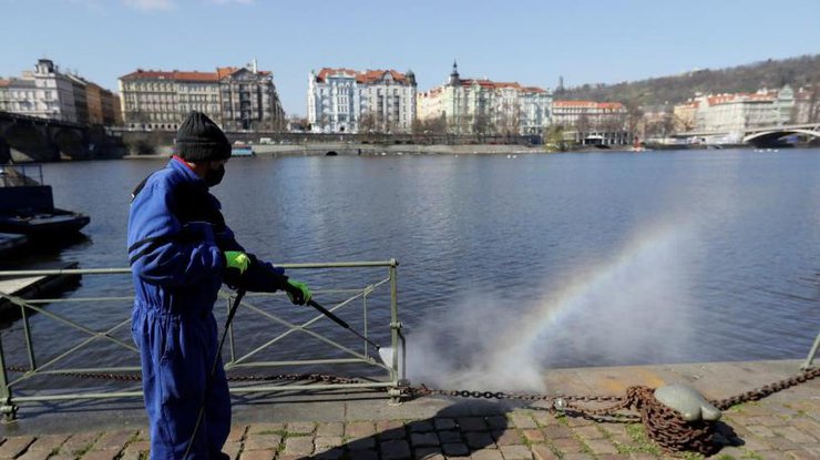 Работник муниципалитета распыляет дезинфицирующее средство на набережной в Праге, 1 апреля 2020 года/REUTERS
