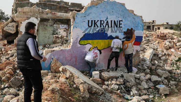 Сирийские художники рисуют фреску в знак солидарности с Украиной на стене разрушенного дома после российского вторжения в Украину.