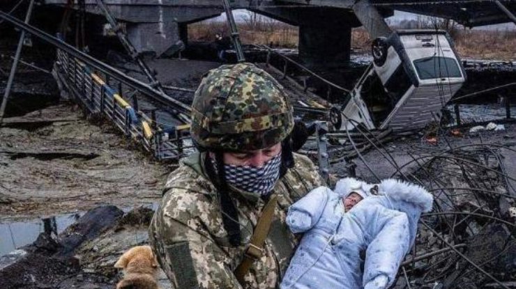 Военный несет ребенка у разрушенного моста в Ирпене / Фото: CNN