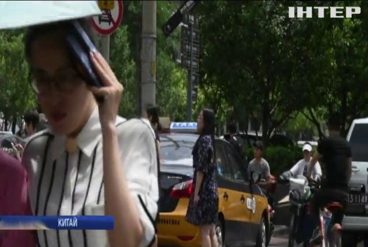 Спека у Китаї: жителі рятуються парасольками