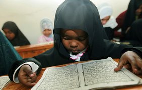 Кенийский ребенок читает Коран в пятый день мусульманского святого месяца Рамадан в Madrassa, Кения