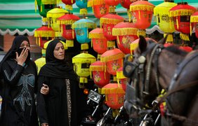 Египтянки идут мимо бумажных фонарей, которыми оформляют улицы в центре Каира во время Рамадана
