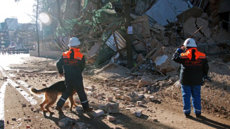 Кинологи с собаками обследуют руины обрушившейся части здания в центре Харькова