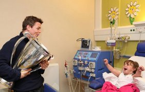 Ирландская звезда регби Брайян Дрисколл навещает юную болельщицу в больнице с кубком Хайнекен.