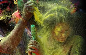 Мужчина осыпает женщину цветной пудрой во время празднования Холи в Мумбаи, Индия, 17 марта 2014 года.