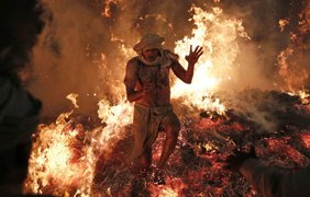 Индуистский священнослужитель совершает ритуал, символизирующий сожжение демона Холики, во время празднования Холи в деревне Пхален, Индия, 17 марта 2014 года.