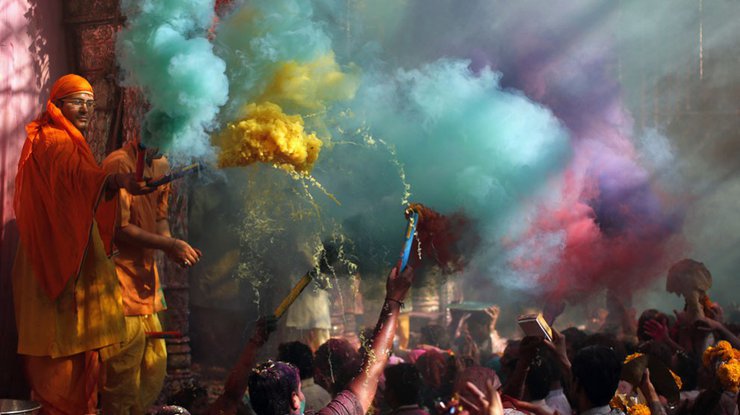 Священнослужители осыпают индуистов цветной пудрой во время празднования Холи возле храма Банке-Бихари во Вриндаване, штат Уттар-Прадеш, Индия, 13 марта 2014 года.