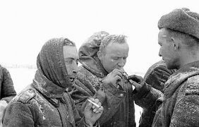 Советский боец дает прикурить пленным немцам.