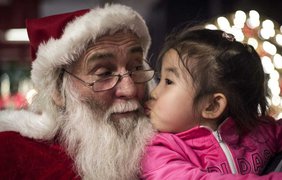 Девочка целует Санта Клауса в гостинице Intercontinental в Пекине, Китай, 19 декабря 2014 года.