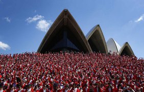 Тысячи энтузиастов позируют для группового снимка после ежегодного забега Санта Клаусов от Дарлинг-Харбора до Сиднейского оперного театра, 7 декабря 2014 года.