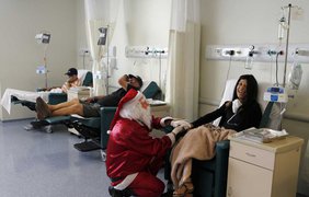 Санта Клаус беседует с женщиной, которая проходит химиотерапию, в Институте онкологии (Cancer Institute) в Сан-Паулу, Бразилия, 19 декабря 2014 года.
