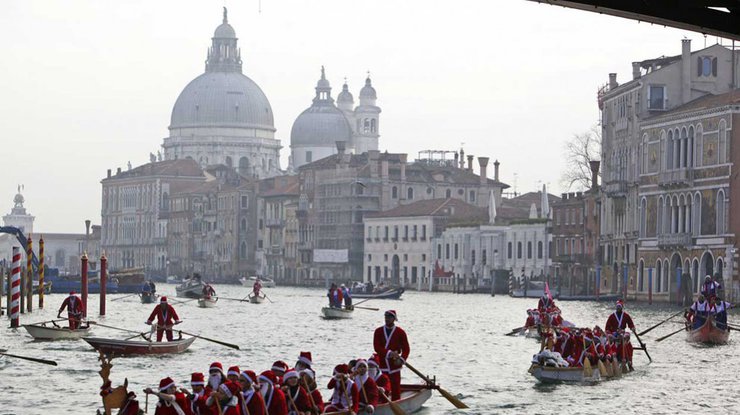 Люди в костюмах Санта Клауса плывут на гондолах по Венецианской лагуне, 20 декабря 2014 года.