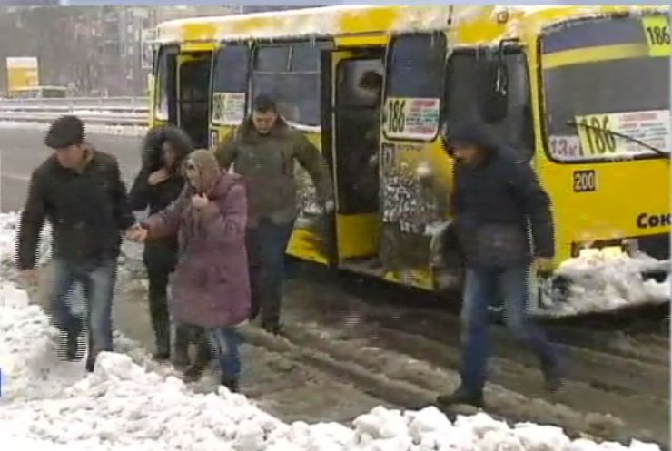 Снігопад у Києві: пасажири на зупинках перестрибують через півметрові кучугури